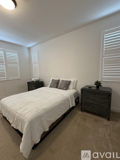 A bedroom with a bed, nightstand, and window with blinds.