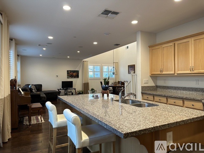 A kitchen with a granite countertop and white chairs.