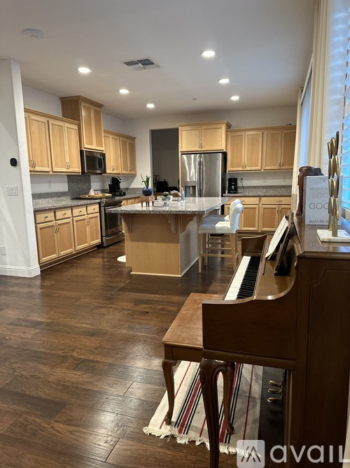 A kitchen with wooden cabinets and a piano in the foreground.