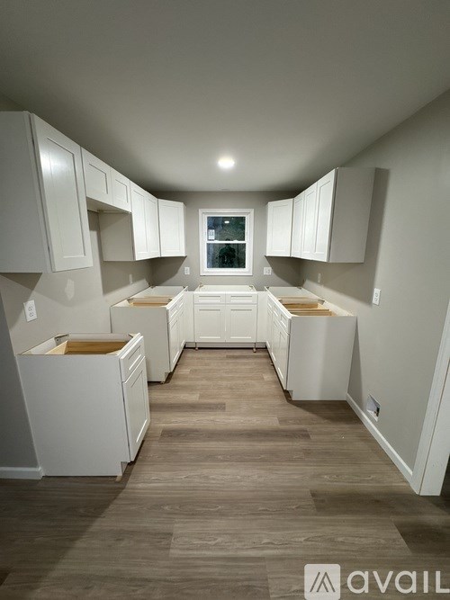 A kitchen with white cabinets and wooden floors.