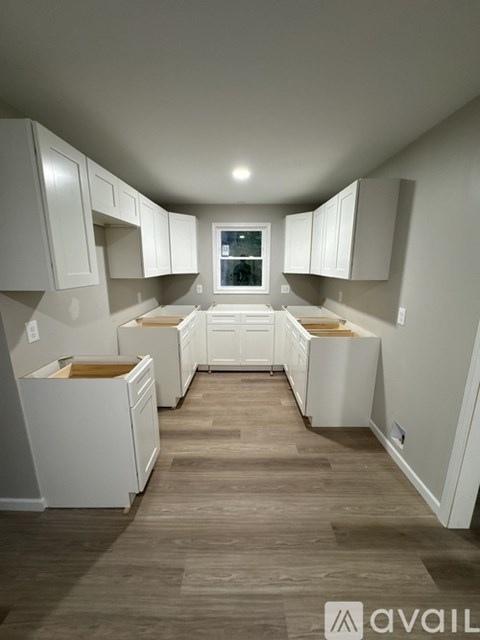 A kitchen with white cabinets and wooden floors.