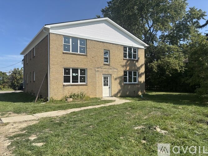 A small brick house with a white door and windows.