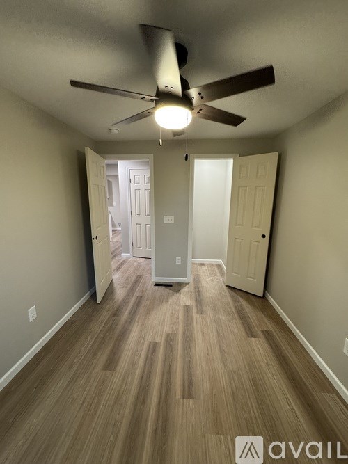 A room with a ceiling fan and light fixture, and two doors, one of which is open.