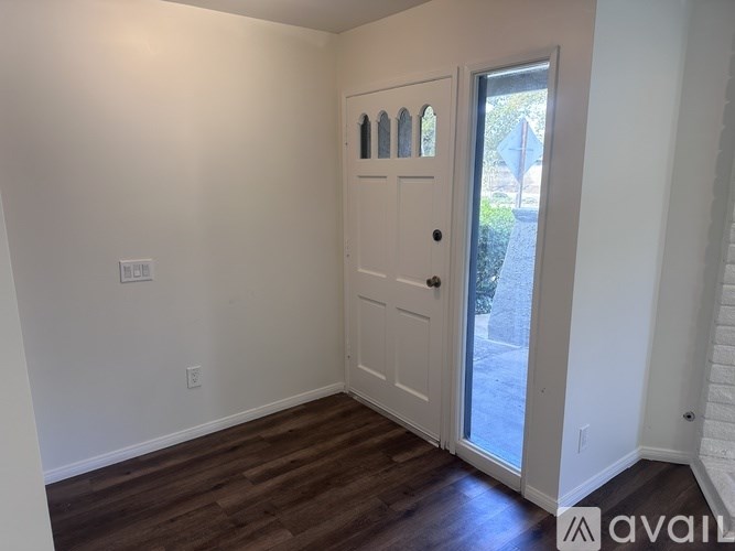 A room with a white door and a window showing a street view.