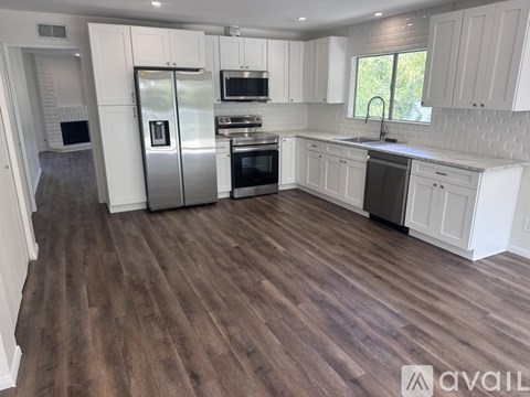 A kitchen with white cabinets and a wooden floor.