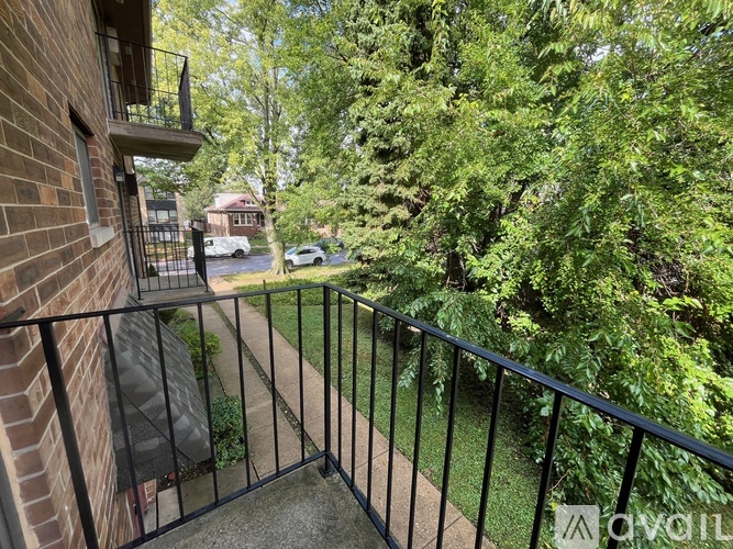 A balcony with a black railing overlooks a residential street.