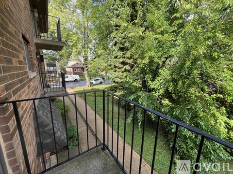 A balcony with a black railing overlooks a residential street.