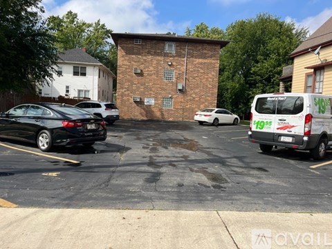 A parking lot with a brick building and a white van with the word "Signs" on it.