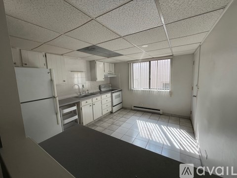 A kitchen with white cabinets and appliances is available for rent.