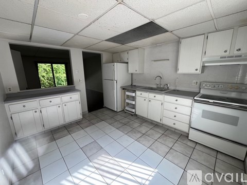 A kitchen with white cabinets and appliances is available for rent.