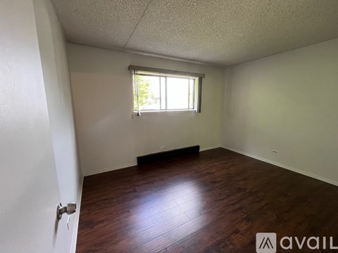 A room with wooden flooring and a window letting in light.