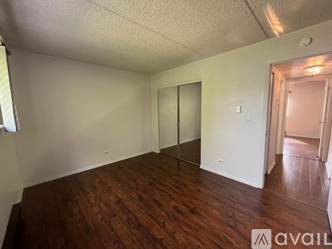 A room with wood flooring and a white wall with a door and a window.
