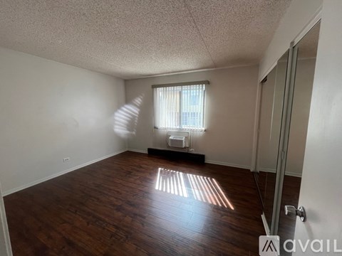 A room with wooden floors and a window with blinds.