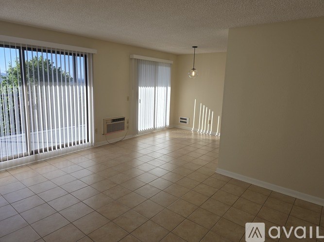 A spacious room with tiled flooring and a large window with blinds.