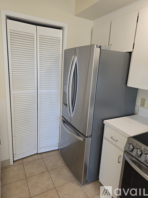 A kitchen with a stainless steel refrigerator and white cabinets.