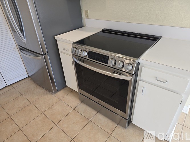 A stainless steel refrigerator stands next to a white oven and stove in a kitchen.