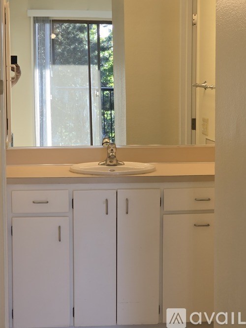 A bathroom with a sink, mirror, and cabinets.