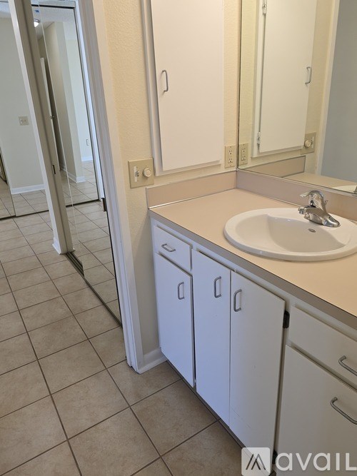 A bathroom with a sink, mirror, and cabinets.
