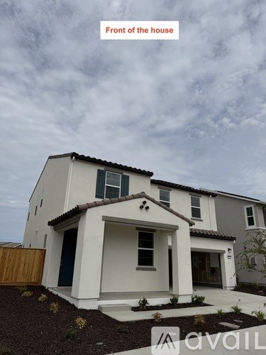 A white house with a brown roof and a brown fence in front of it.