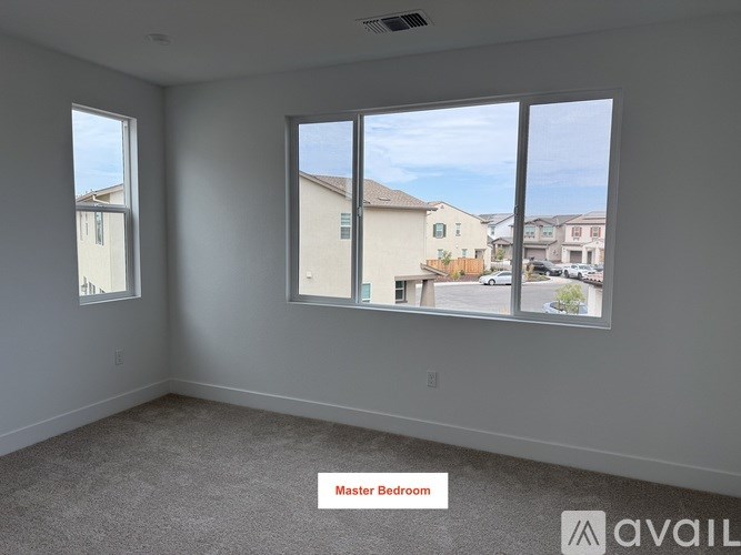 A master bedroom with a large window overlooking a residential area.