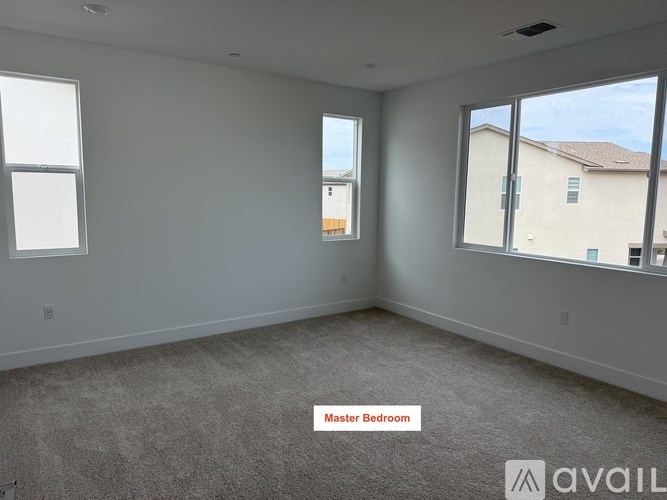 A spacious master bedroom with carpeted floor and large windows.