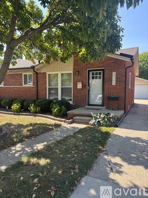 A house with a front yard and a tree in front of it.