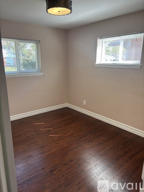 A room with wooden floors and two windows.
