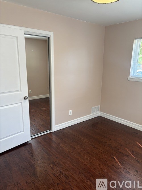 A room with a white door and wooden flooring.