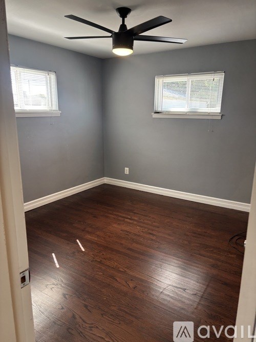 A room with a ceiling fan and wooden flooring.