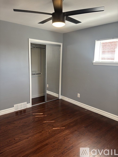 A room with a ceiling fan and wooden floors.