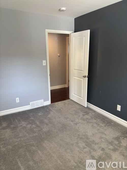 A room with a carpeted floor and a doorway leading to another room.