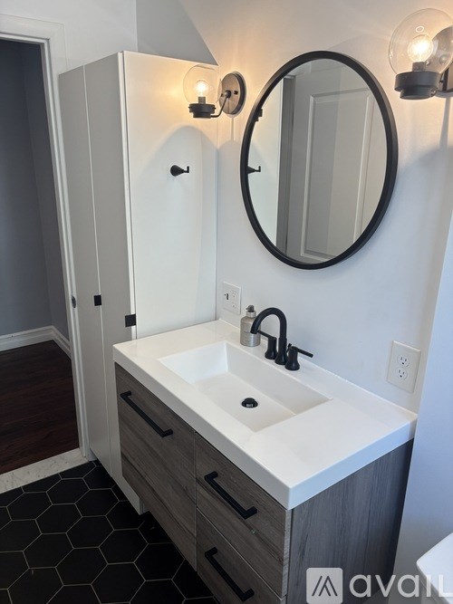 A bathroom with a sink, mirror, and light fixtures.
