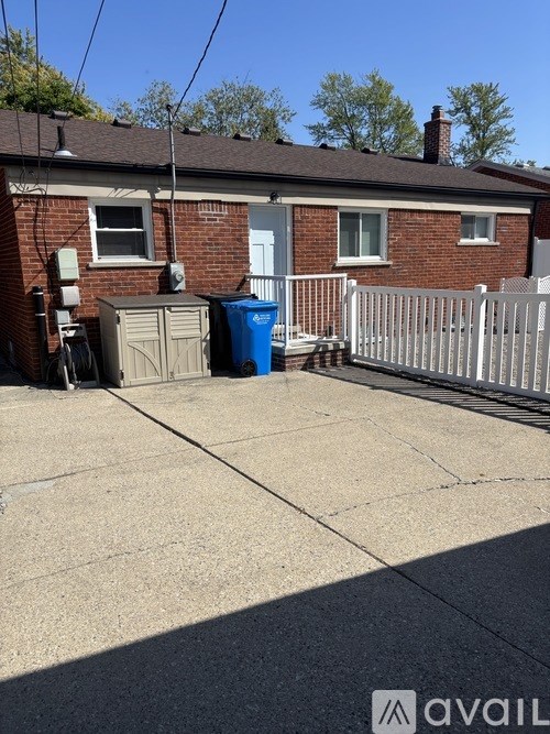 A house with a blue trash bin in front of it.