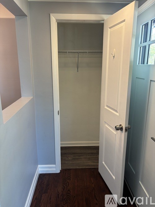A white door with a silver handle is open to a hallway.
