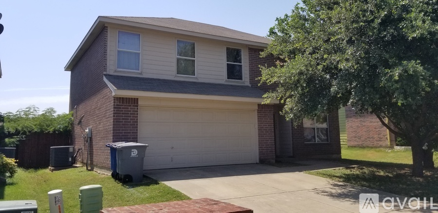 A house with a grey garage door and a tree in front.