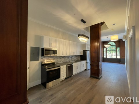 A modern kitchen with wooden floors and white cabinets.