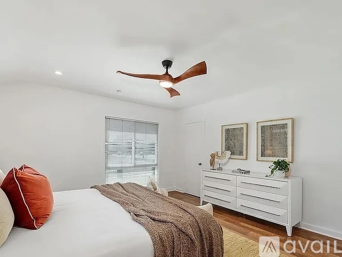 A bedroom with a bed, a ceiling fan, and a dresser with a mirror.