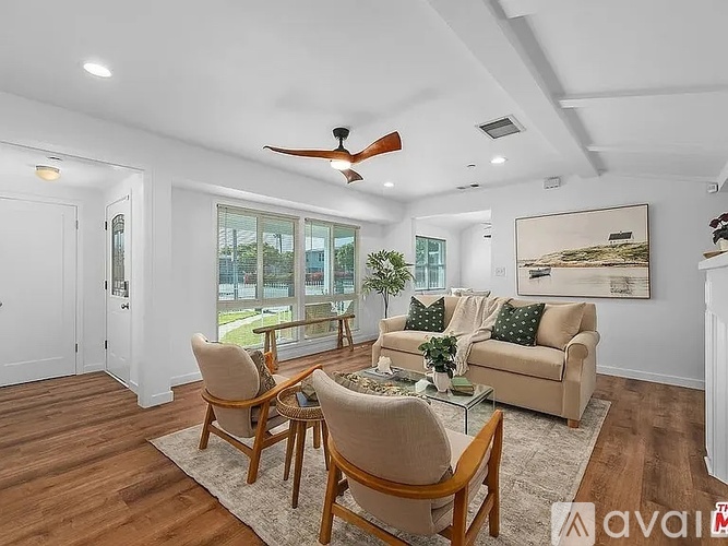 A living room with a couch, chairs, and a ceiling fan.