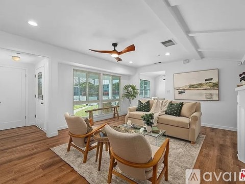 A living room with a couch, chairs, and a ceiling fan.