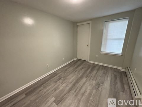 A room with wooden flooring and a window with blinds.