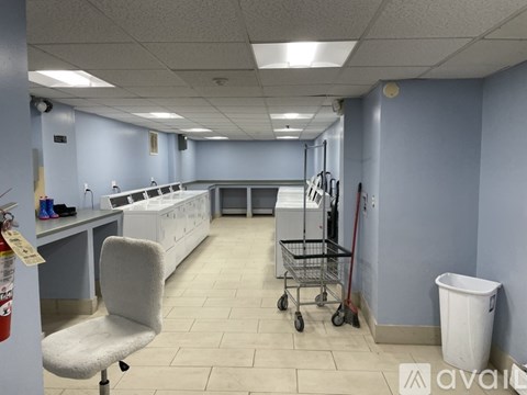 A clean, empty room with a white chair and a white trash can.