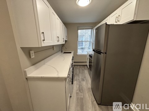 A kitchen with white cabinets and a black refrigerator.