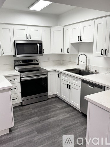 A kitchen with white cabinets and a black microwave.