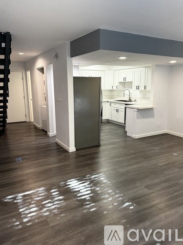 A kitchen with a white fridge and cabinets is shown.