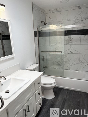 A bathroom with a marble wall and a glass shower stall.