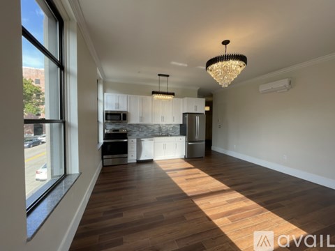 A well-lit, spacious kitchen and living room with hardwood floors and a large window.