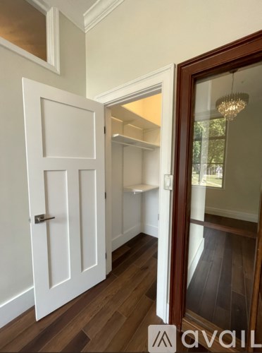 A white door with a silver handle is in a room with wooden floors.