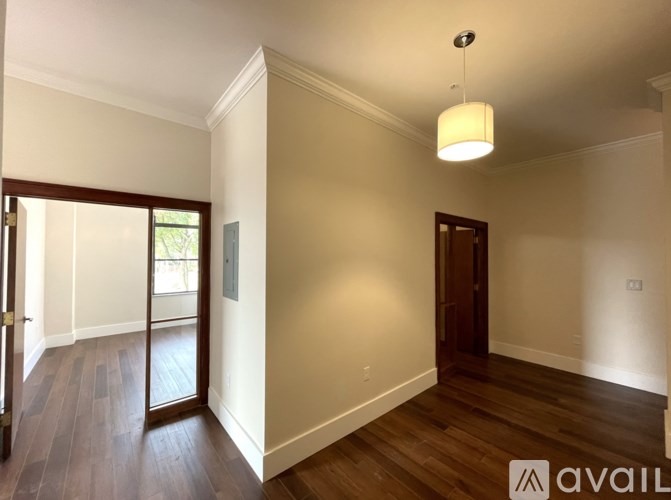 A room with wooden floors and a white ceiling with a hanging light fixture.