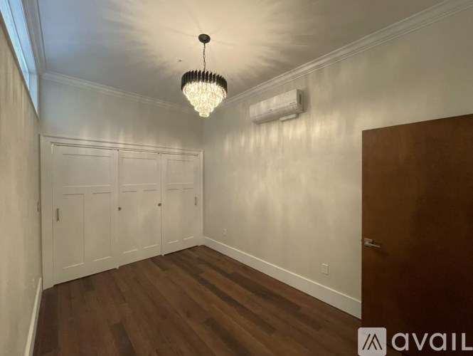 A room with a chandelier, two doors, and a wall-mounted air conditioner.
