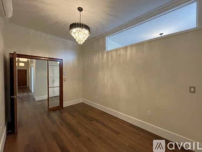 A room with wooden floors and a chandelier hanging from the ceiling.